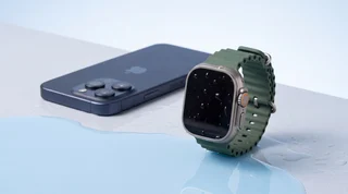 A refurbished iPhone, Google Pixel and Apple Watch lined up on the wet edge of a pool with water droplets on their screens