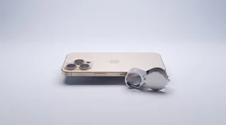 A refurbished iPhone beside a jeweller's loupe, ready to be checked before you buy