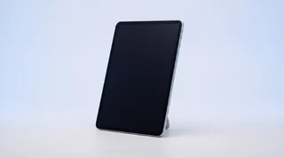 A single iPad propped upright on a clean studio surface with its screen dark and asleep