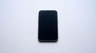 A single iPhone lying on a clean studio surface with its screen dark and asleep